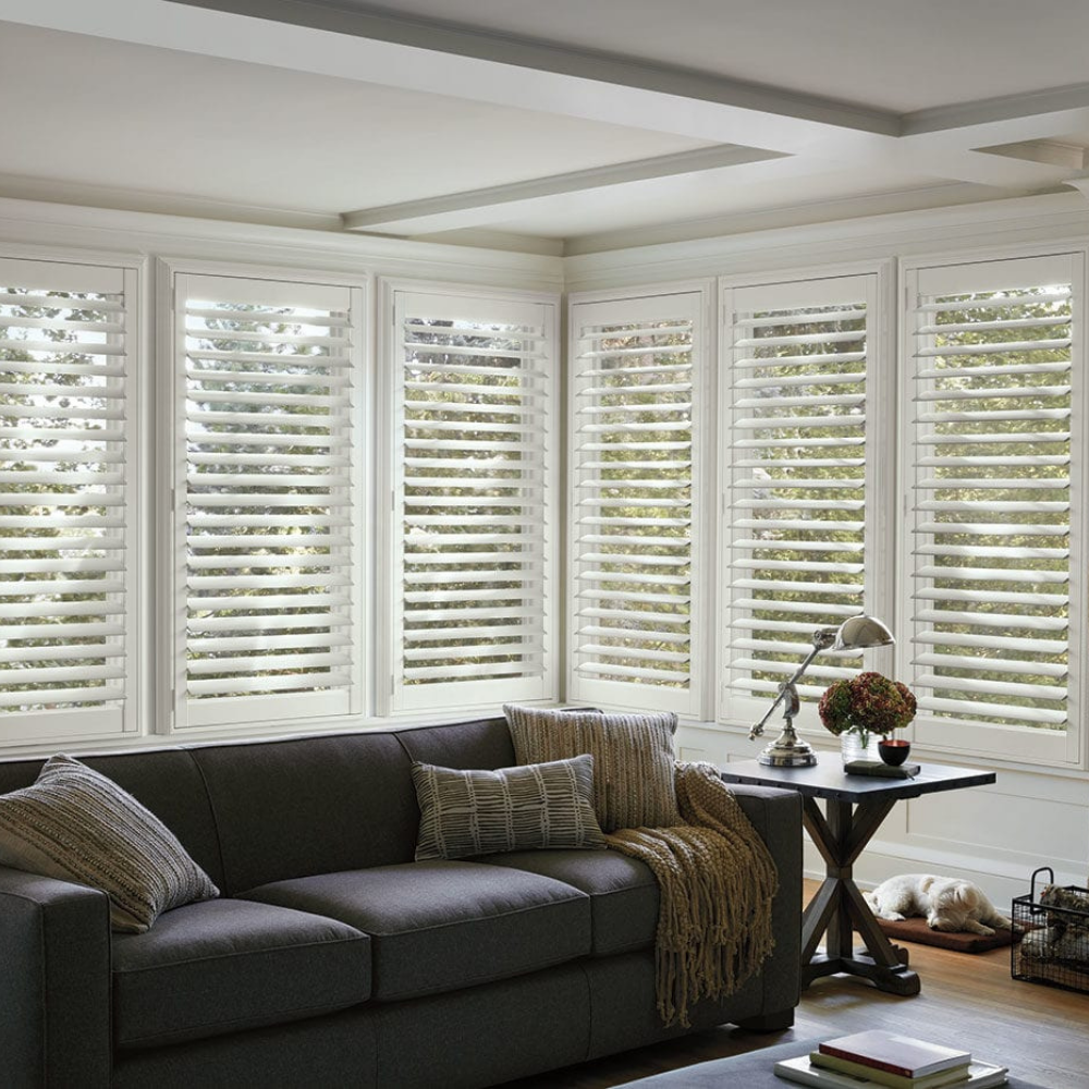 Hunter Douglas NewStyle shutters in the corner of a living room. Available at JC Licht in Chicagoland